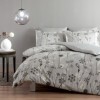 Lenjerie de pat cu imprimeu floral delicat în nuanțe de gri pe fundal deschis, compusă din pilotă și perne decorative asortate.
