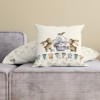Față de pernă decorativă din bumbac 100%, 45x45cm, cu doi iepurași adorabili decorând un ou pascal, pe fundal crem cu ghirlande festive.