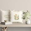 Față de pernă decorativă din bumbac 100%, 45x45cm, cu iepuraș îmbrăcat în rochiță florală, încadrat de flori de primăvară, pe fundal bej deschis, ideală pentru decor pascal.