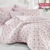 Lenjerie de pat cu design floral roz și verde pe fundal alb, completată de fețe de pernă asortate și modele mici de flori.