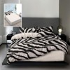 Lenjerie finet crem cu imprimeu dungi zebra alb-negru si cearceaf bej, asezata pe pat modern.