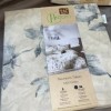 Lenjerie de pat dublu bumbac 100% reciclat TAC Reborn Naia cu design floral în nuanțe de gri și alb pe fundal bej