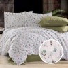 Lenjerie de pat dublu din bumbac 100% creponat, cu imprimeu floral pastel în tonuri de roz, bleu și verde, prezentată pe pat matrimonial cu fundal rustic-modern