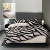 Lenjerie finet cu imprimeu zebra alb-negru si cearceaf drept crem, asezata pe pat modern