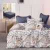 Lenjerie finet gri deschis cu imprimeu linii geometrice si cearceaf drept bleumarin, asezata pe pat modern