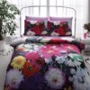 Lenjerie de pat Flowers din bumbac 100% satinat cu design vibrant de flori colorate pe fundal negru și violet.