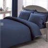 Lenjerie de pat TAC Stripe de culoare albastru închis, cu design în dungi fine, pe un pat alb