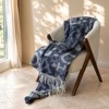 patura Muna Albastra First Choice Daily 200x220 cm cu litere mari bleumarin gri si franjuri decorativi asezata pe fotoliu