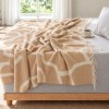 patura Sumina Crem First Choice Daily 200x220 cm cu model geometric crem alb si franjuri decorative asezata pe fotoliu