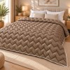 Pilota pufoasa matlasata maro cappuccino 200x220 cm Ralex Pucioasa, cu model in zigzag si paspoal alb, asezata pe pat matrimonial