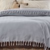 Pled Sidney gri 200x220cm din bumbac reciclat, cu ciucuri groși, așezat pe pat dublu