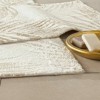 Set de 2 covorașe de baie Tac PasPas Palm bej model frunze tropicale,  plasate pe podea de baie alături de papuci