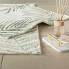 Set de 2 covorașe de baie Tac PasPas Palm verde model frunze tropicale,  plasate pe podea de baie alături de papuci