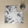 Set de 2 covorașe de baie Tac PasPas Pyra gri model geometric modern, plasate pe podea de baie alături de papuci