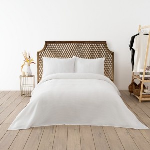 Cuvertura waffle alba 200x220cm asezata pe pat dublu, cu doua fete de perna asortate, in decor luminos si natural