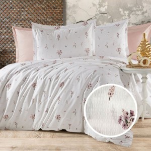 Lenjerie de pat creponata din bumbac 100% cu imprimeu floral delicat in nuante roz-lila, asezata pe un pat matrimonial cu fundal pastel