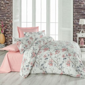 Lenjerie de pat dublu din bumbac 100% creponat, cu imprimeu floral de magnolii roz și frunze gri, prezentată pe fundal cu perete de cărămidă și decor feminin romantic