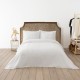 Cuvertura waffle albastra 200x220cm asezata pe pat dublu, cu doua fete de perna, in decor modern cu accente naturale