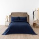 Cuvertura waffle alba 200x220cm asezata pe pat dublu, cu doua fete de perna asortate, in decor luminos si natural