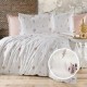 Lenjerie de pat creponata cu imprimeu floral bleu pe fundal alb, din bumbac 100%, asezata pe un pat matrimonial in decor natural si luminos