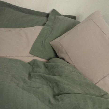Set Vilo Verde – cuvertură pique verde și fețe pernă bej brodate, expus pe pat