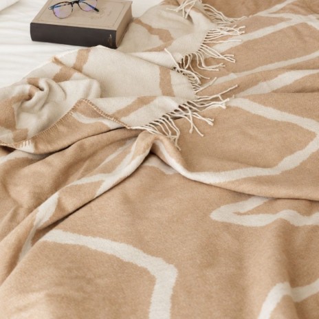 patura Sumina Crem First Choice Daily 200x220 cm cu model geometric crem alb si franjuri decorative asezata pe fotoliu